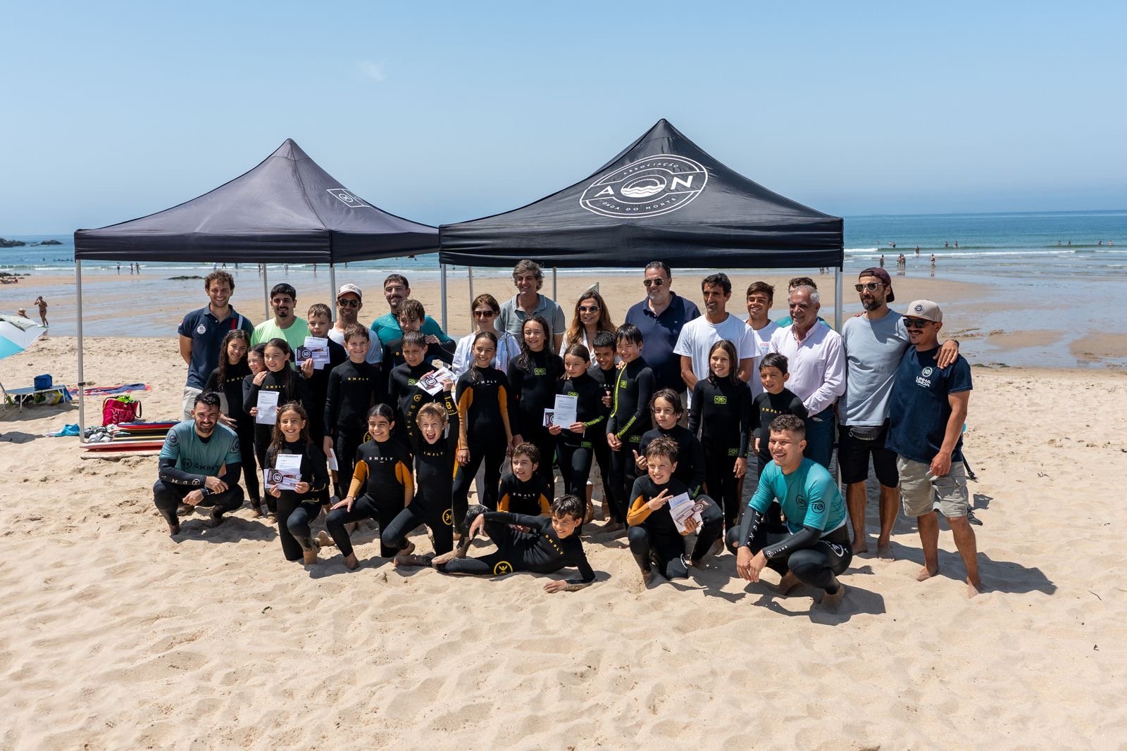 Jovens atletas e equipa técnica reunidos na praia
