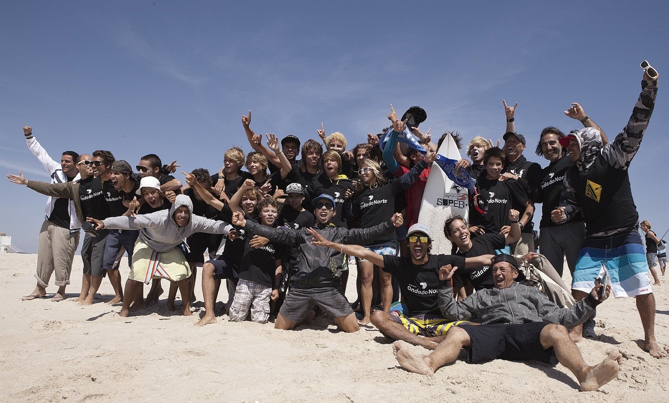 Grande grupo de atletas e apoiantes da Onda do Norte a celebrar na praia